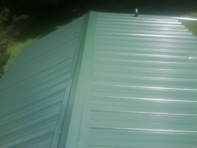 New green metal panels meeting at the ridge of a roof — Flat Roof Repair work by our crew in North Palm Springs
