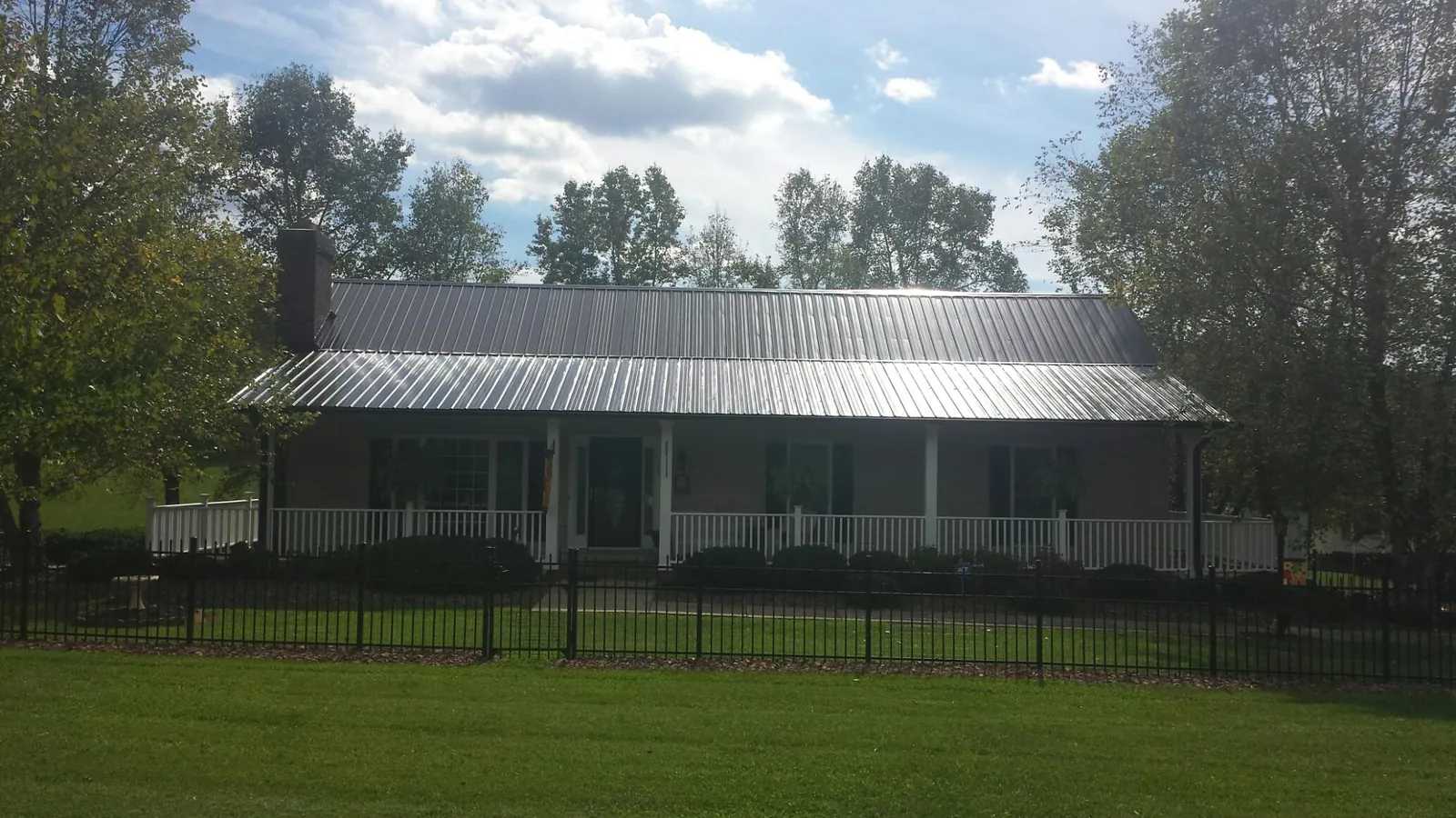 Gray metal roof on a brick ranch with a full width front porch — Gutter Guard Installation work by our crew in North Palm Springs