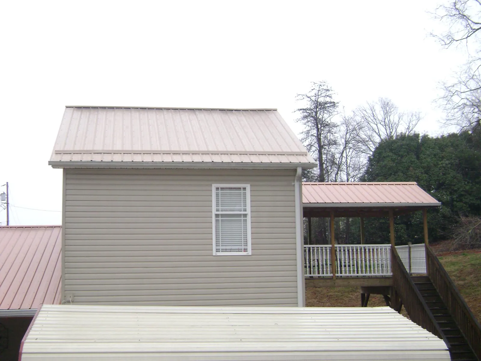 Tan metal roofs on a two story addition and attached porch, from a Roof Replacement job in North Palm Springs