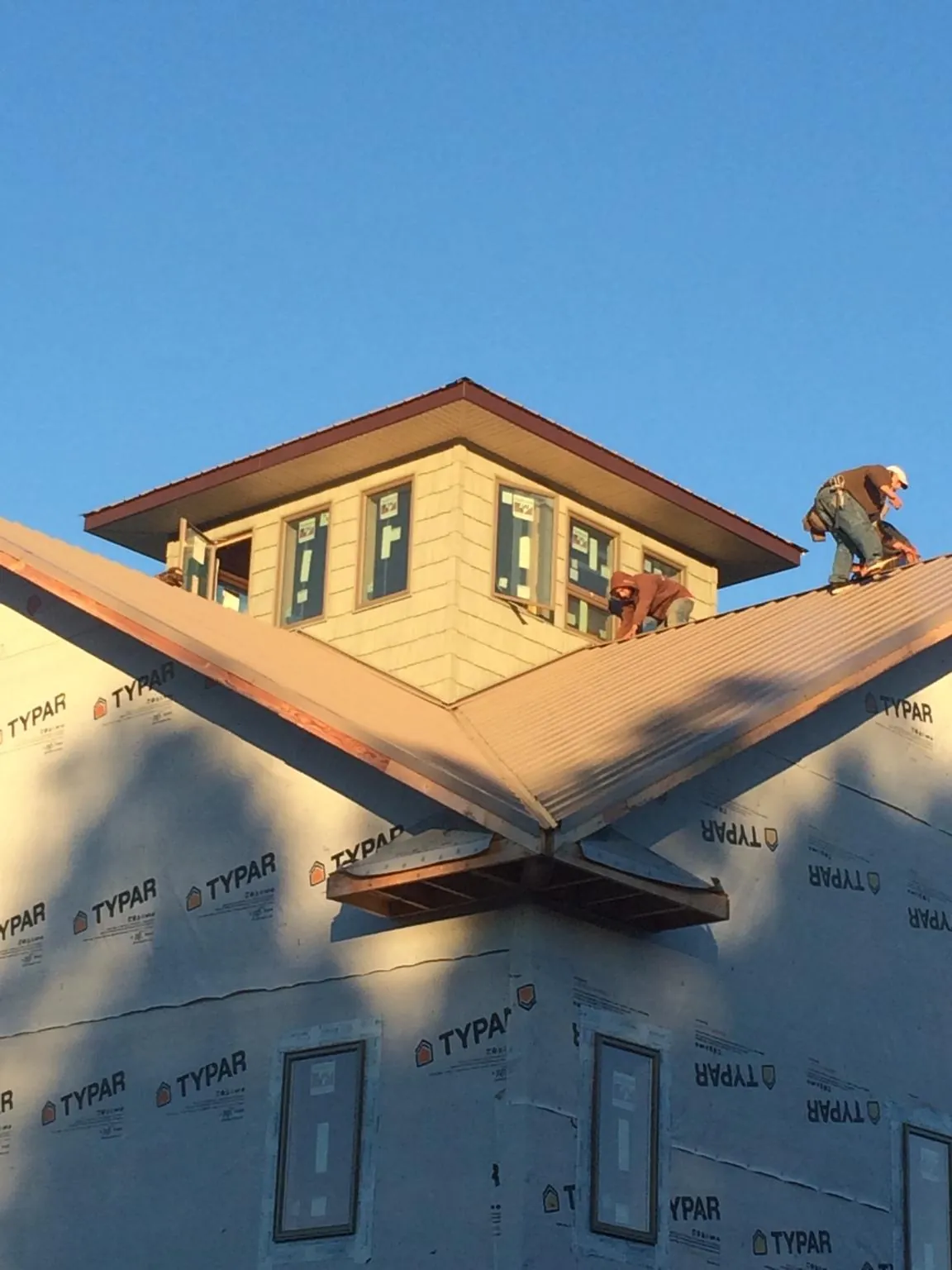 Roofers working around a rooftop cupola on a new metal roof at sunset — Roof Waterproofing in North Palm Springs by Roofing Brothers
